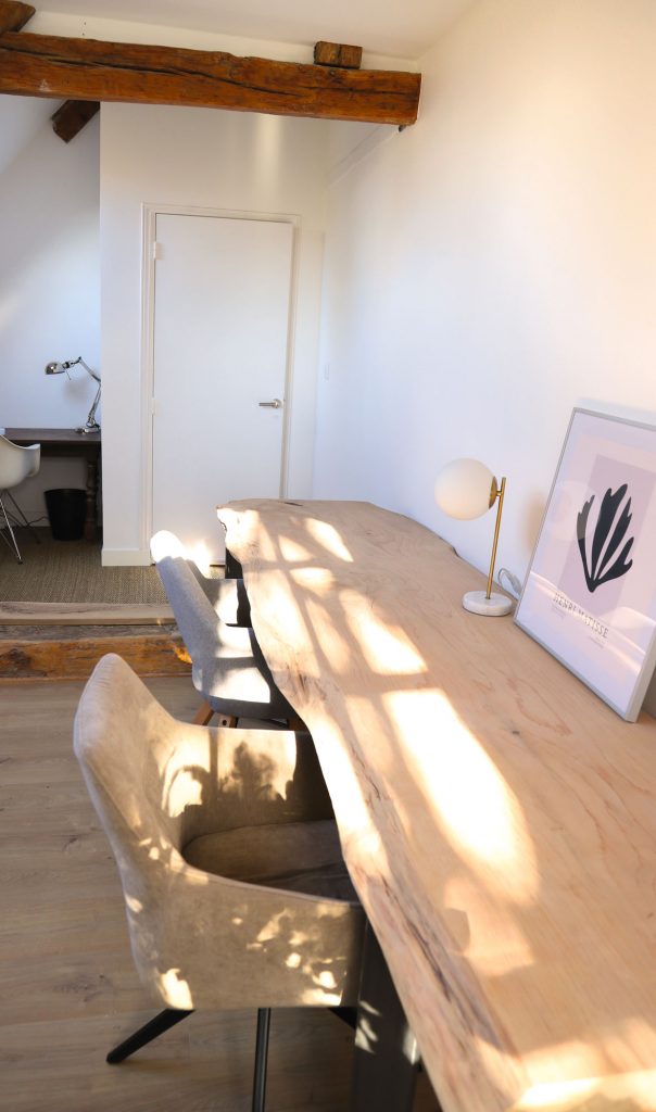 Un bureau en planche de bois massif qui baigne dans la lumière du jardin